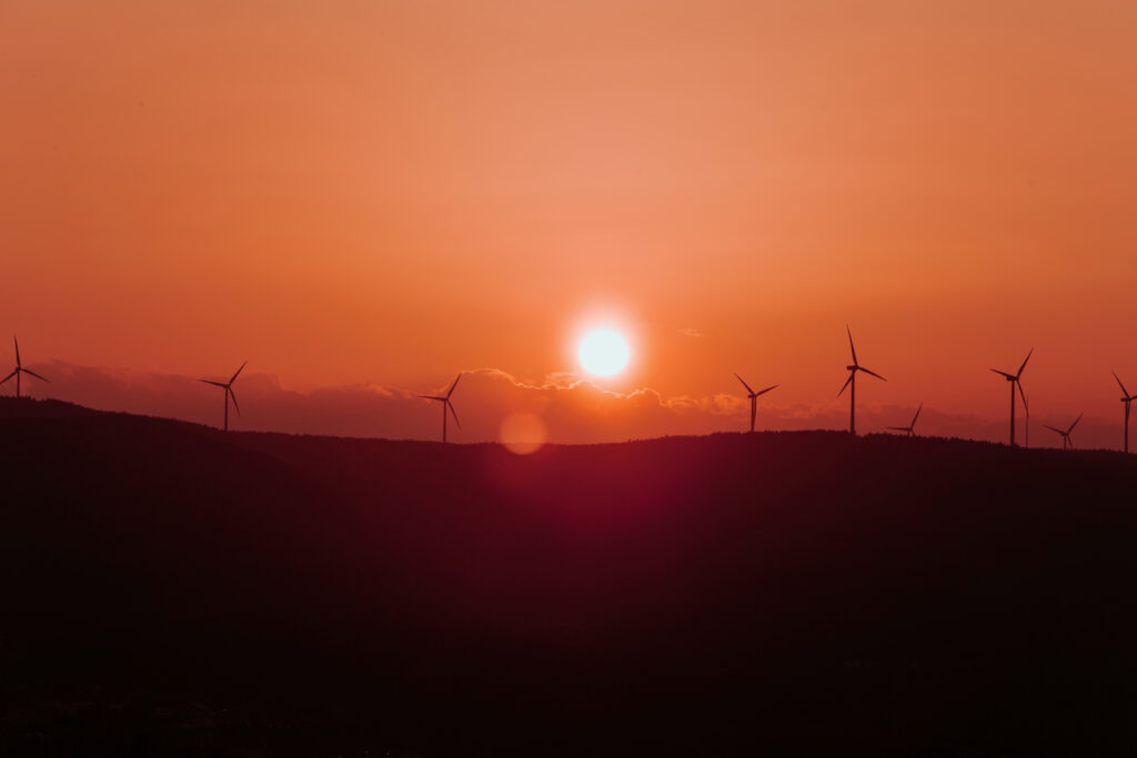 Silhouettes of some wind mills on the top of a mountain during a super orange sunset with copy space peaceful